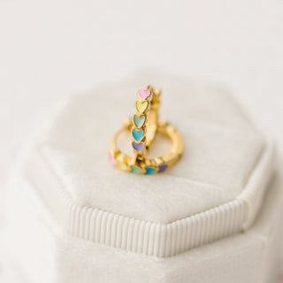 Pierced Co. Rainbow Heart Huggies
Gold ring with colorful heart-shaped stones on a white surface