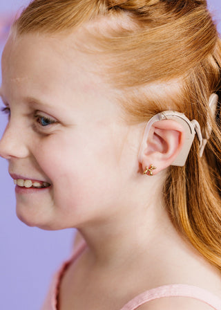 Pierced Co Earrings - Balloon Dog
Young girl wearing a hearing aid with a purple background