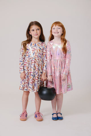 Pink Chicken Girls Lame Steph Dress - Pink Spider Web
Two young girls wearing colorful dresses standing against a plain background