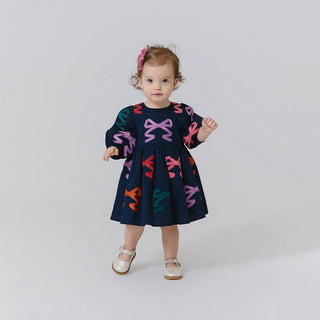 Pink Chicken Baby Girls Brooke Dress Set - Multi Bow Applique
Child wearing a navy dress with colorful bow patterns on a white background