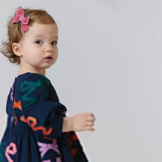 Pink Chicken Baby Girls Brooke Dress Set - Multi Bow Applique
Child wearing a dark blue garment with colorful patterns on a plain background