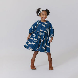 Pink Chicken Girls Katya Dress - Wild Horses
Child wearing a blue dress with white horse pattern and brown boots on a plain background