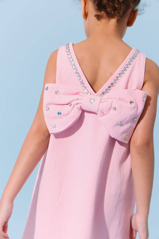 Pink denim dress with a crystal heart embellishment and bow detail from Lola & The Boys, perfect for stylish young girls.