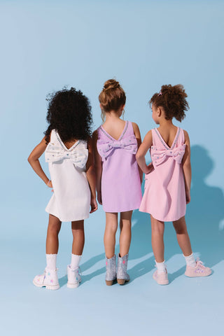 Pink denim dress with a heart-shaped crystal embellishment and bow detail from Lola & The Boys.