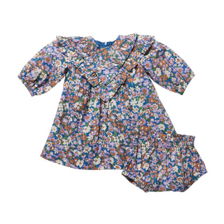Pink Chicken Baby Girls Everly Dress Set - True Blue Sketched Floral
A baby girl's long-sleeve dress with a colorful floral print, featuring ruffled trim at the neckline and a matching ruffled bloomers leg, laid flat on a light gray background.