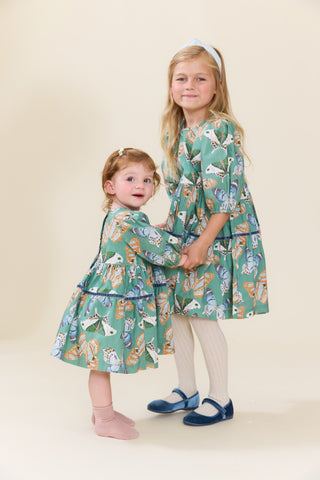 Pink Chicken Girls Maribelle Dress - Green Butterflies
Two young girls modeling matching green patterned dresses with a whimsical animal print, standing against a solid cream background.