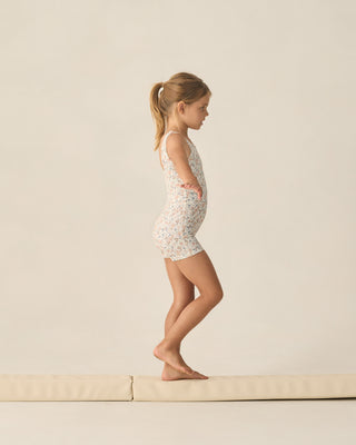 Play by Rylee & Cru Malibu Bodysuit - Flower Field
Young girl in a floral swimsuit standing on a beige platform against a plain background