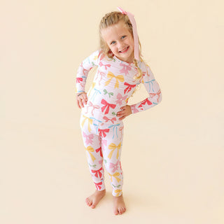 Posh Peanut Classic Pajama Set - Shawna
Child wearing a colorful bow-patterned onesie on a beige background
