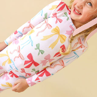 Posh Peanut Classic Pajama Set - Shawna
Child wearing a colorful bow-patterned outfit on a beige background