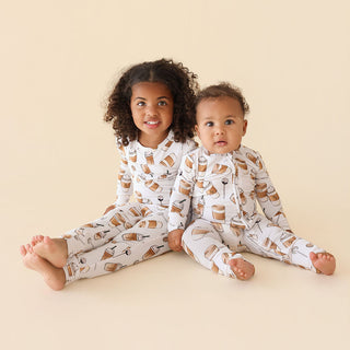 Posh Peanut Coffee Classic Pajama Set
Two children wearing pajamas with a pattern of cups and cookies on a beige background