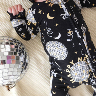 Posh Peanut Convertible One Piece - Midnight Bash 
Child wearing a black outfit with disco ball and party hat pattern, next to a disco ball.