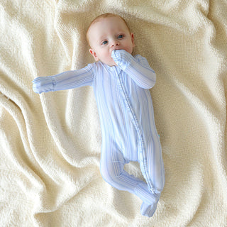 Posh Peanut Footie Zippered One Piece - Richie
Baby in a light blue outfit lying on a beige blanket