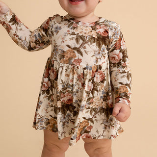 Posh Peanut Long Sleeve Twirl Bodysuit Dress - Dauphine
A toddler wearing a long-sleeve floral dress with a gathered waist, photographed against a solid beige background.