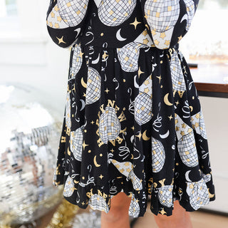 Posh Peanut Ruffle Twirl Dress - Midnight Bash
Black dress with white and gold pattern in a store setting