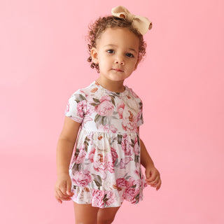 Posh Peanut Ruffled Twirl Bodysuit Dress - Lucienne
Child wearing a floral dress against a pink background