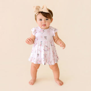 Posh Peanut Ruffled Twirl Bodysuit Dress - Piroutte
Baby wearing a floral dress and headband on a beige background