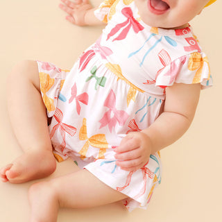 Posh Peanut Ruffled Twirl Bodysuit Dress - Shawna
Baby wearing a colorful floral dress on a beige background
