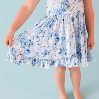 Posh Peanut Ruffled Twirl Dress - Trista
Child wearing a floral dress with blue flowers on a light blue background