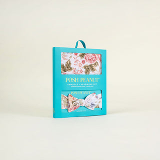 Posh Peanut Swaddle Headband Set - Kristiana
A turquoise retail box for a Posh Peanut swaddle and headwrap set, shown upright on a clean off-white background. The front of the box has a floral swaddle window and a smaller headwrap window, with the brand name 'POSH PEANUT' printed in gold.