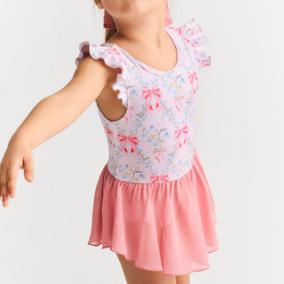 Posh Peanut Twirl Skirt Leotard - Harriet
A young girl wearing a pink and white floral print dance leotard dress with ruffled cap sleeves and a matching pink tutu skirt, shown from the neck down against a light gray background.
