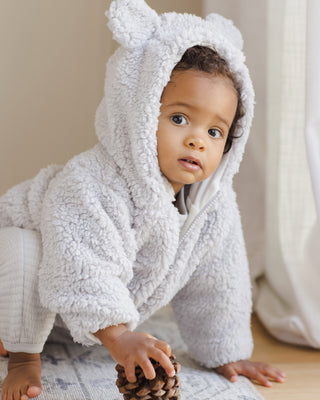 Quincy Mae Bear Jacket - Frost
Baby in a white fleece onesie with bear ears, sitting on a light-colored surface.