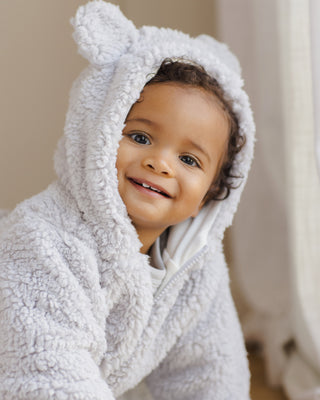 Quincy Mae Bear Jacket - Frost
Child wearing a white hooded towel with bear ears, smiling indoors.