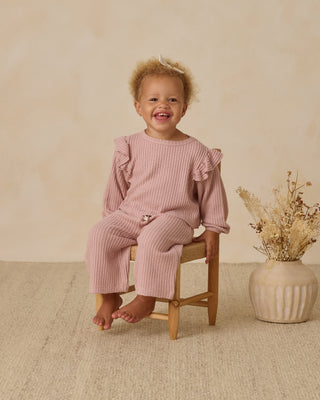 Quincy Mae Ruffle Cozy Set - Rose
Child wearing a pink ribbed outfit sitting on a wooden stool with a neutral background