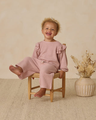 Quincy Mae Ruffle Cozy Set - Rose
Child wearing a pink outfit sitting on a chair with a vase of flowers in the background