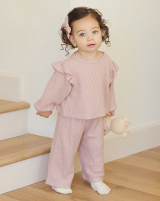 Quincy Mae Ruffle Cozy Set - Rose Child wearing a pink ribbed outfit standing on a wooden floor.