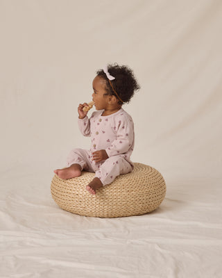 Featuring our 'hearts' print on our 'lilac' hue.
Child sitting on a woven stool against a plain background