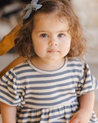 Quincy Mae Darla Dress - Ocean Stripe
Young girl wearing a striped dress with a blurred background