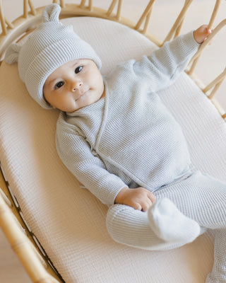 Quincy Mae Baby Bear Beanie - Ice Blue
Baby in a light gray outfit lying in a crib