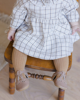 Quincy Mae Simone Dress - Blue Plaid
Child wearing a plaid dress and brown shoes sitting on a wooden chair.