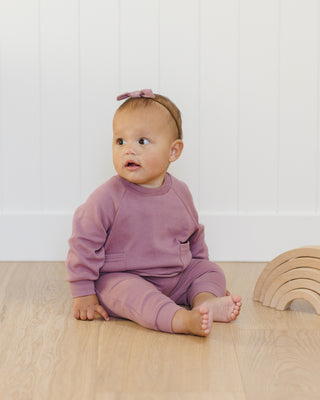 Quincy Mae Pocket Sweatshirt & Sweatpant Set - Mulberry
Baby in a pink outfit sitting on a wooden floor with a white wall background