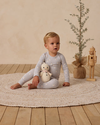 Quincy Mae Bamboo Pajama Set - Snowmen
Child sitting on a rug holding a plush toy in a room with a plant and nutcracker decoration.