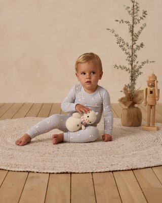 Quincy Mae Bamboo Pajama Set - Snowmen
Child sitting on a rug holding a teddy bear in a room with a plant and wooden toy.