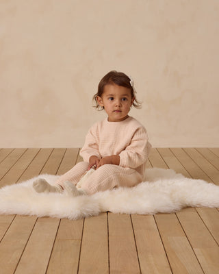 Quincy Mae Textured Sweat Set - Antique
Child in a pink outfit sitting on a white rug with a beige background