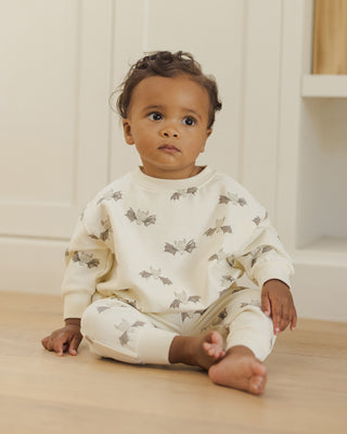 Quincy Mae Relaxed Fleece Sweatshirt & Relaxed Sweatpant Set - Bats
Baby sitting on a wooden floor wearing a white outfit with gray patterns.