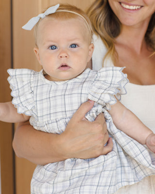 Quincy Mae Alina Dress - Blue Plaid
Baby in a checkered outfit held by a smiling woman