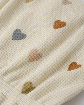 Quincy Mae waffle cinch romper in ivory with confetti hearts pattern, featuring a comfortable fit and cute design for babies.