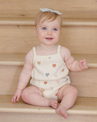 Quincy Mae waffle cinch romper in confetti hearts pattern, featuring soft fabric and adjustable waist for comfortable baby wear.
