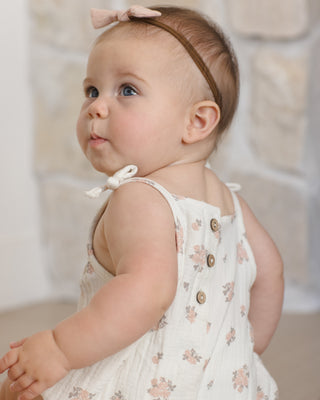 Quincy Mae Betty Romper - Garden Rose
Baby wearing a white floral dress with a bow headband against a neutral background