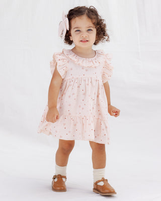 Quincy Mae Charlotte Dress - Heart Confetti
Young girl wearing a pink dress with ruffled sleeves on a white background