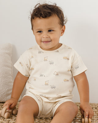Quincy Mae Frankie Set - Construction
Baby wearing a white onesie with car prints sitting on a woven mat.