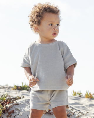 Quincy Mae Terry Top + Short Set - Sage
Child wearing a light gray shirt and shorts on a sandy beach.