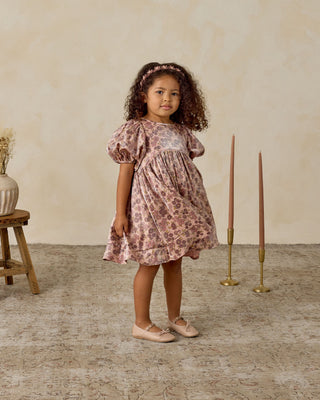 Noralee Luna Dress - Harvest Fleur
Young girl in a floral dress standing in a room with a wooden stool and candles.