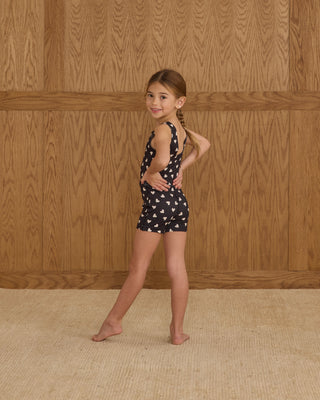 Play by Rylee & Cru Malibu Bodysuit - Hearts
Young girl in a black and white patterned romper standing against a wooden paneled wall.