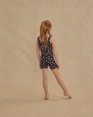 Play by Rylee & Cru Swift Sports Bra - Hearts
Young girl wearing a navy blue romper with white patterns on a beige background