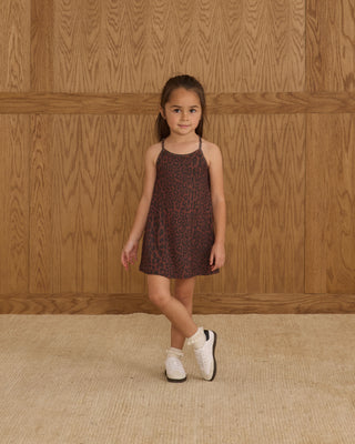 Play by Rylee & Cru Loma Dress - Leopard
Young girl in a patterned dress standing against a wooden paneled wall.