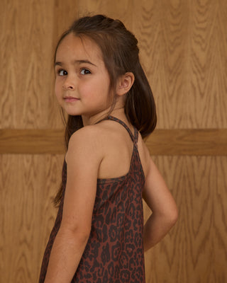 Play by Rylee & Cru Loma Dress - Leopard
Young girl wearing a patterned dress against a wooden paneled wall